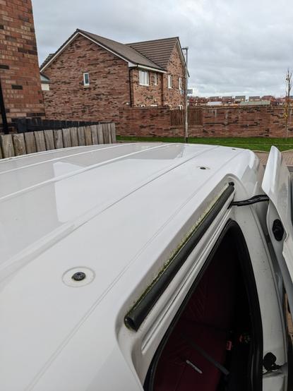 Top of a white VW Caddy van showing the roof rack bolts.