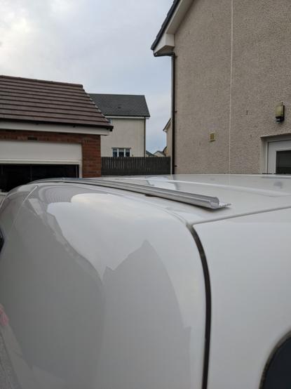 Roof of a white VW Caddy from the rear with an awning rail attached.