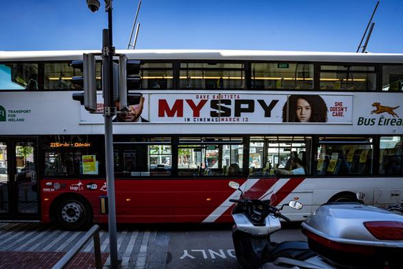 A double decker bus with an advert for the film "My Spy" on the side of the vehicle.