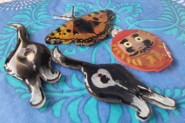 Two black and white cats, a red round daruma doll, and an orange butterfly. They are glossy and partially translucent.