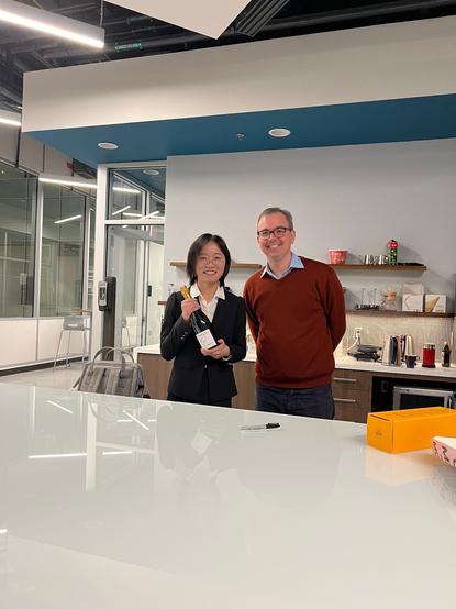 New PhD holding her celebratory PhD champagne bottle next to her advisor