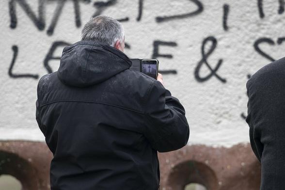 Detlef Walk (Nationaler Widerstand Zweibrücken) fotografiert die antifaschistischen Graffiti, die wenige Tage zuvor auf das Mahnmal gesprüht wurden.