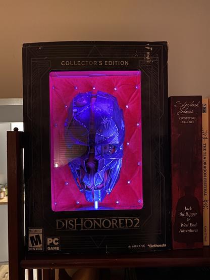 A photo of the Dishonored 2 collectors edition. It’s set up to look like a display case for the skull-like mask of Corvo Attano. The box has been modified with lighting and a plush velvet lining.