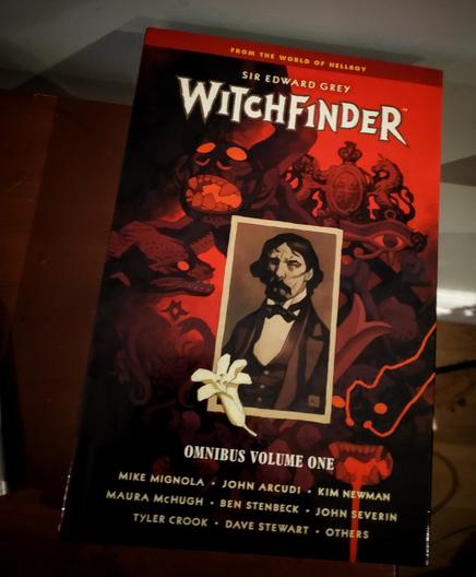 Photo of a comic Omnibus entitled "Sir Edward Grey: Witchfinder." The cover shows a photo of a mustachioed man in Victorian garb overlaid on a monochromatic black & red background depicting monsters.