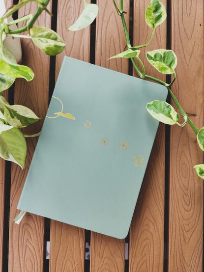 A green planner with gold foil images of the sun and cherry blossoms