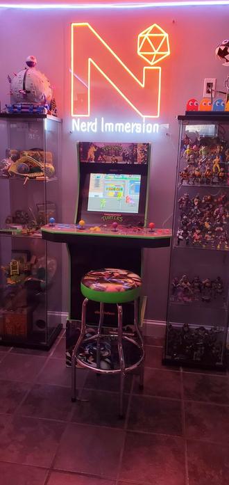 Nerd Immersion neon sign amongst TMNT memorabilia and TMNT arcade cabinet