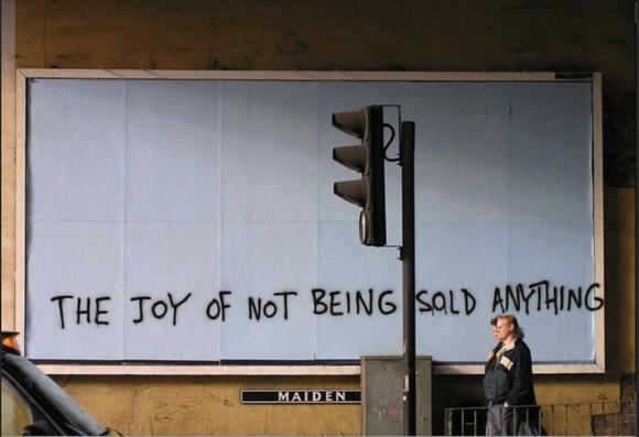 graffiti on a blank billboard says: the joy of not being sold anything