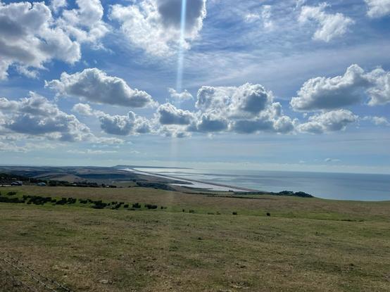 View to Portland Dorset from Jurassic Coast. Billowy clouds and sun.