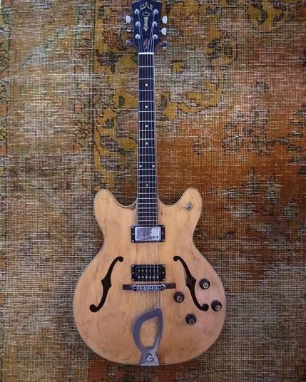 Guild Starfire guitar. Semi-HollowBody guitar with f-holes, two pickups and 4 tone/volume controls. Silver tailpiece in the shape of a harp. Finish is blonde.