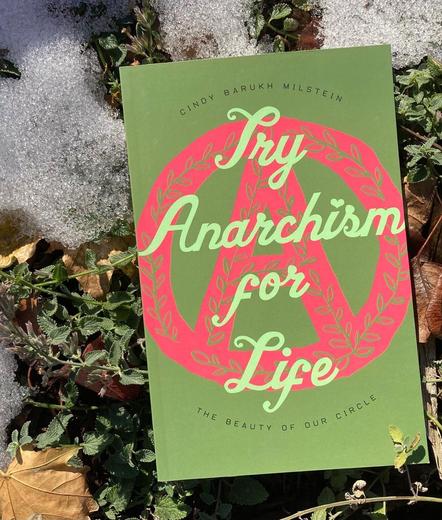 Book cover with two tones of green, with the title “Try Anarchism for Life” overlaid on a bright pink circle A drawing that has a slight floral print into it, with book set on green plants near a bit of snow.