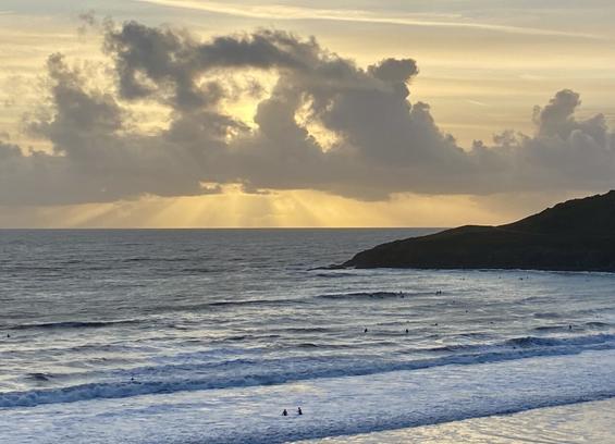 Surfers and swimmers bobbed in distant Langland Bay as heavenly sunbeams shone from behind a cloud in the apricot evening sky.