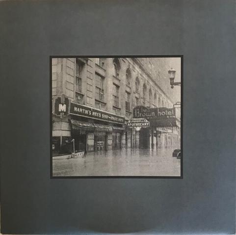 The cover art of ‘As Performed by Aerial M’, showing a flooded street scene in black and white.