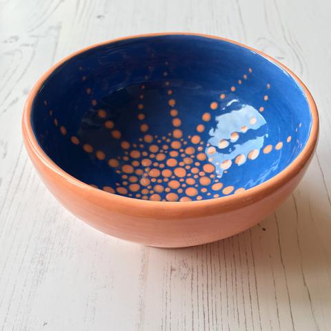 Earthenware wheel thrown bowl. Orange exterio and blue inside with radiating orange dots to the rim.