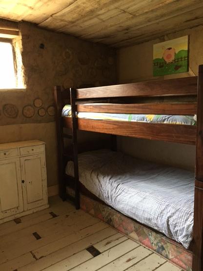 Inside the bunk room of the Happy Pig.  Two of the four bunk beds shown, a window and a painting of a smiling happy pig inside the wood/cob structure!