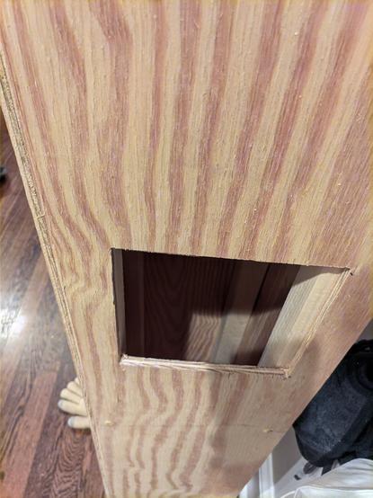 Zoomed on on the tower on a different side, there's a 6x6 inch square hole mid-way up the tower. Some 2x2 piece of lumbers are partially visible on two different corners, giving the plywood something to connect to and giving it stability & structure.