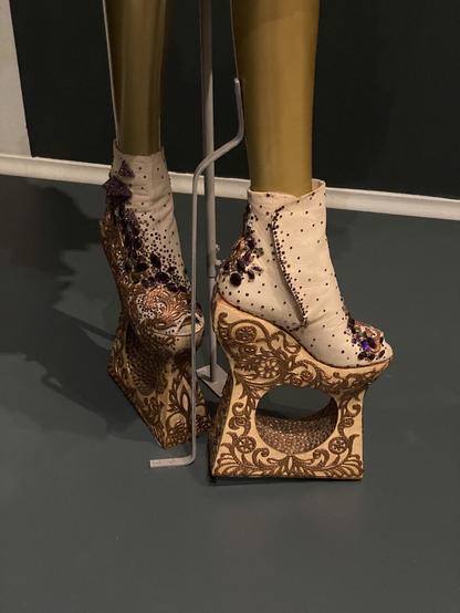 Beaded and embroidered booties, with very high platform soles with a hole carved through the center, so the shoe almost appears to be floating.