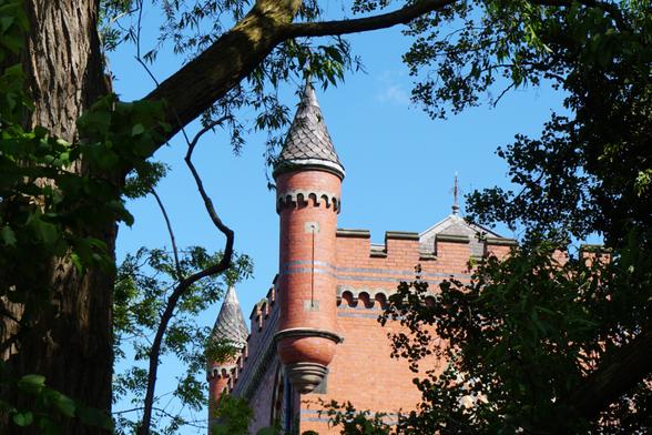 A view of a water pumping station through trees. red and blue victorian brickwork, crenelated around the roof with towers on the corners. Some fine examples of Victorian architecture next to the canal near Wombourne in Staffordshire