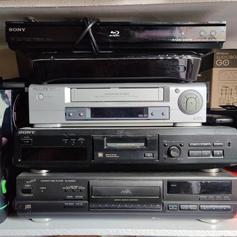 A stack of audio-video equipment. From top to bottom: a Sony Blu-ray player; Humax Freesat PVR; silver Philips VHS recorder; Sony minidisc deck; Technics CD deck.