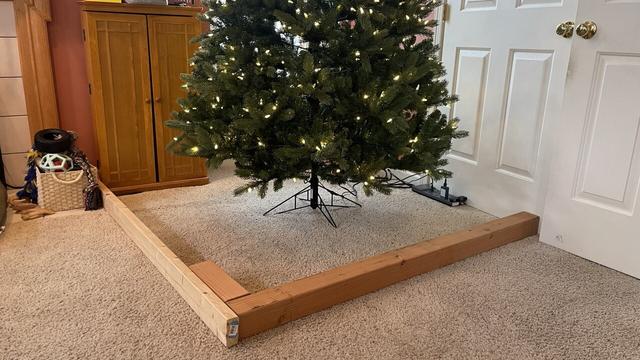 2 x 4 and 4 x 4 walls erected around the base of a holiday tree protecting it from the home’s shark robot vacuum