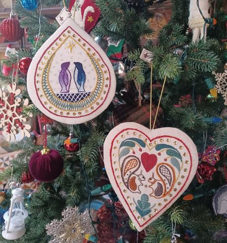 2 embroidered Christmas ornaments featuring "twin" animals: penguins on one and squirrels on the other. Stitched by Elizabeth C. Bunce