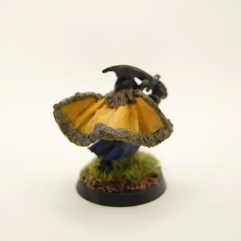 A painted miniature of a dwarf flourishing a cape and brandishing a sabre.