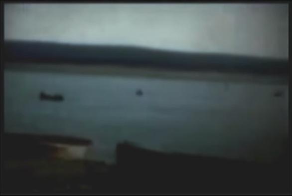 An excerpt from the film, showing very old found footage of a blue country lake, and various small boats on the shore and in the water.