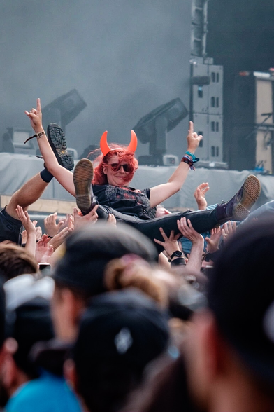 Une personne avec des cornes de diable sur la tête se fait porter par la foule du public du Hellfest.