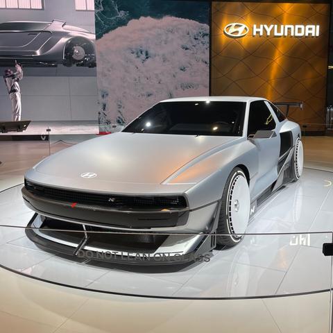 A grey sleek sports car on a white turntable. The car is a Hyundai N Vision 74 concept car from the 2022 LA Auto Show