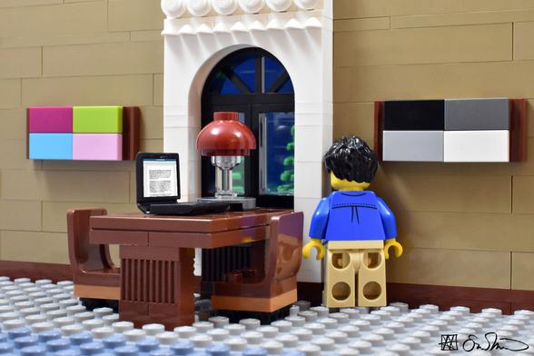 LGS has his laptop with a document open, which is placed on a table beside him in the library. He has his head shoved into a crevice in the wall.