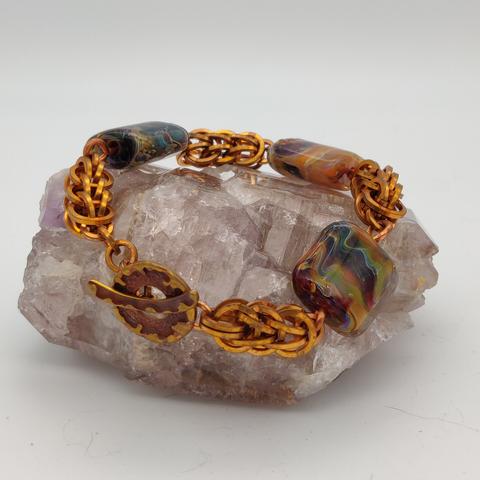 Bronze chainmaille bracelet with lampworked multicolor glass beads and a toggle clasp.