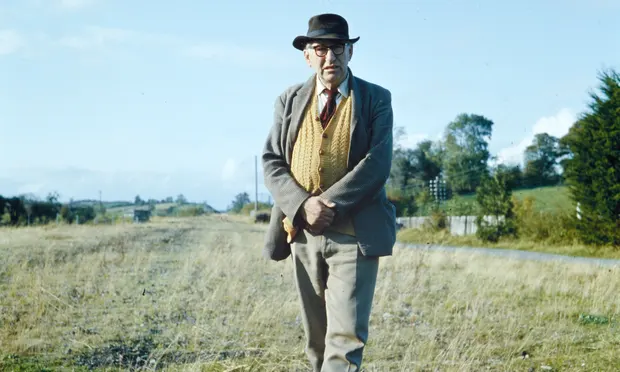 Irish poet Patrick Kavanagh in a field wearing a hat and a jacket.
