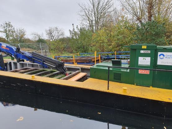 Old doors on a barge, with a second barge behind on which are new doors.