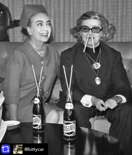 Joan Crawford & Bette Davis, 1962 black and white photo. Joan Crawford and Bette Davis sit together with bottles of PepsiCola on a table in front of them. Each bottle has two straws and Bette has two straws stuck in her nose. Larf.