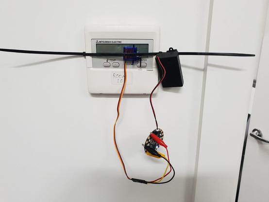 Microprocessor board with a temperature sensor wired into a battery pack and a servo, zip-tied on to a HVAC controller