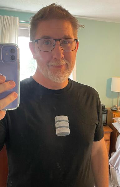 A selfie of me in a shirt with a database icon that look like 3 canisters stacked on one another, representing a disk array.