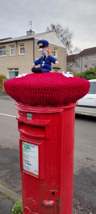 Post box with hand knitted top and a knitted Postman Pat soft toy