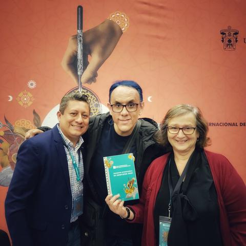 Los refritos Luis Antonio Canché, Alberto Chimal y Clara Obligado sonríen a la cámara, sosteniendo un ejemplar de la antología del Encuentro Internacional de Cuentistas de la FIL Guadalajara.