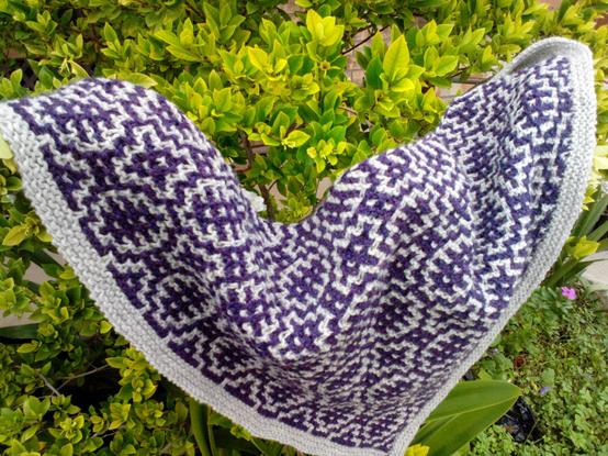 Hand-knit woolen kerchief shawl of purple and dove grey, knit in a slip-stitch mosaic design.