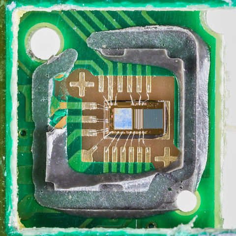 Das Innere der optischen Einheit mit Sender und Empfänger des Infrarots-Lichts). Feinste Drähte aus Gold verbinen die Die (also das Halbleiter-Wafer) des ICs mit den Kontakten zur Außenwelt