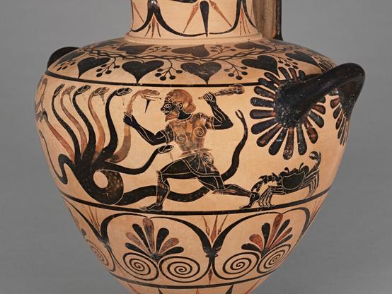 The subject of the figural decoration of this hydria is Herakles and Iolaos slaying the Hydra.
Painted in black figure, the scene occupies the upper register on the body of the vessel between the two side handles. Herakles approaches from the right grasping one of the heads of the nine-headed, bearded Hydra with his left hand and raising his club with his right. Herakles is armored in a corslet and greaves. To his right, a large crab pinches Herakles' heel. Iolaos rushes forward from the left grasping one of the Hydra heads with his left hand and preparing to cut it off with the sickle he brandishes in his right. Underneath Iolaos is a small fire. On the reverse of the vessel, two sphinxes flank the vertical back handle, striding away from the center.