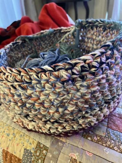 A photo of an unfinished crochet project. It is a multicolored basket.