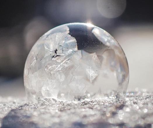 Eine fast vollständig gefrorene Seifenblase im Schnee in der Sonne.