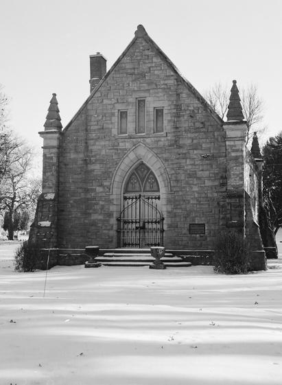 Black & White image of the stone & stained-glass front of a Funeral Chapel in the snow. Forest Hill Cemetary, Eau Claire WI.