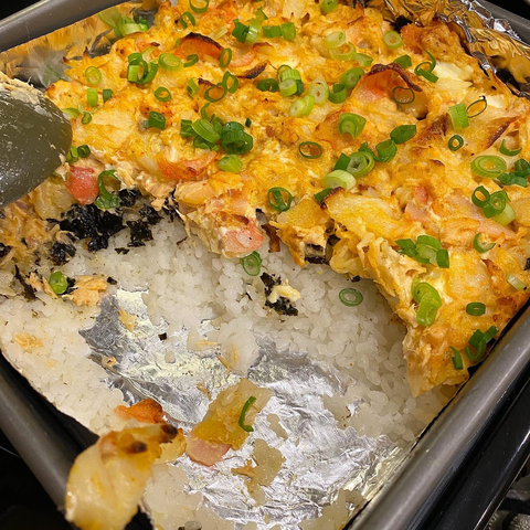 Sushi bake in a metal casserole tray, cross section showing rice, nori, and seafood