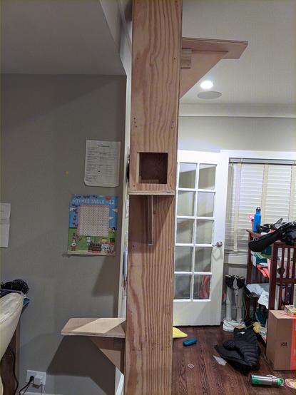 Same cat tower, this time upright. It reaches the ceiling. There are 3 platforms/shelves on the tower, all on different sides.