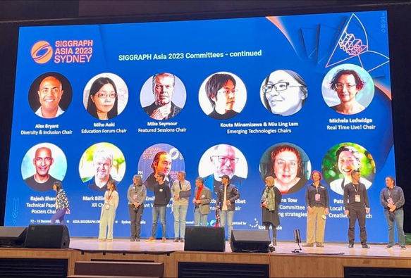 Some of the SIGGRAPH Asia 2023 chairs on stage in front of their photos on screen behind them
