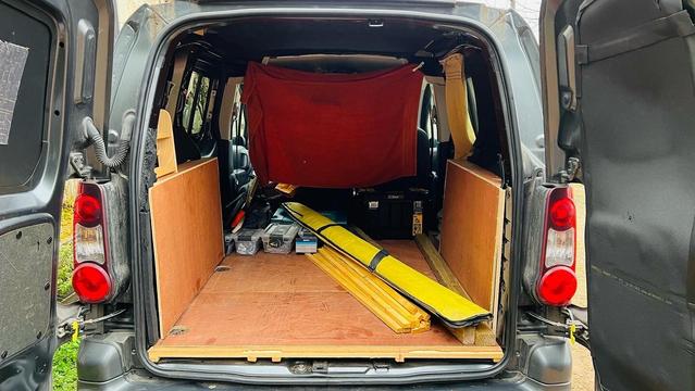 The same van, same view, with some tool boxes and tool bags and timber inside.