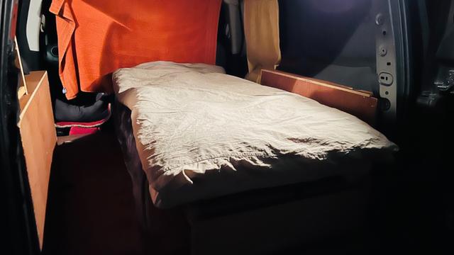 The same van with the single bed made up with linen and duvet, ready to go camping