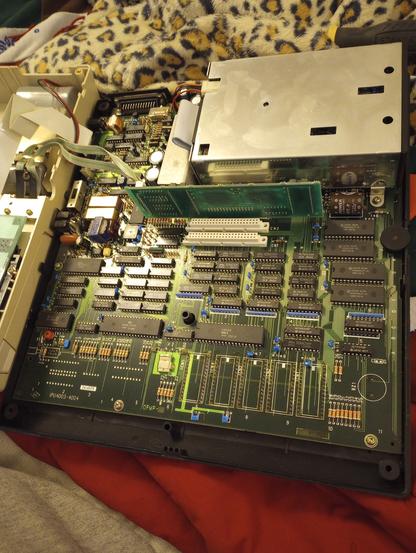 Tandy 600 motherboard. Green with lots of DIPs. A small card sticks up in the middle (32k memory). Has an actual half-height 3.5" floppy drive (same height as a half-height 5.25"drive)