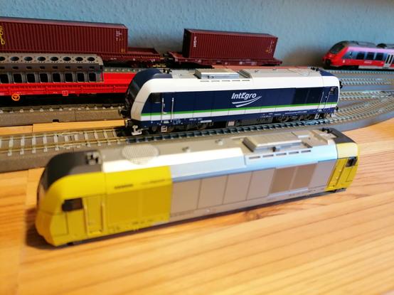 Siemens EuroRunner ER20 223 152-0 der IntEgro (aka. PRESS) in dunkelblau und weißer mit grünem Streifen. Davor ER20-Gehäuse im gelb-silbernen Design von Siemens Dispolok. Dahinter diverse Güterwagen und der Kopf eines ein Talent 2.